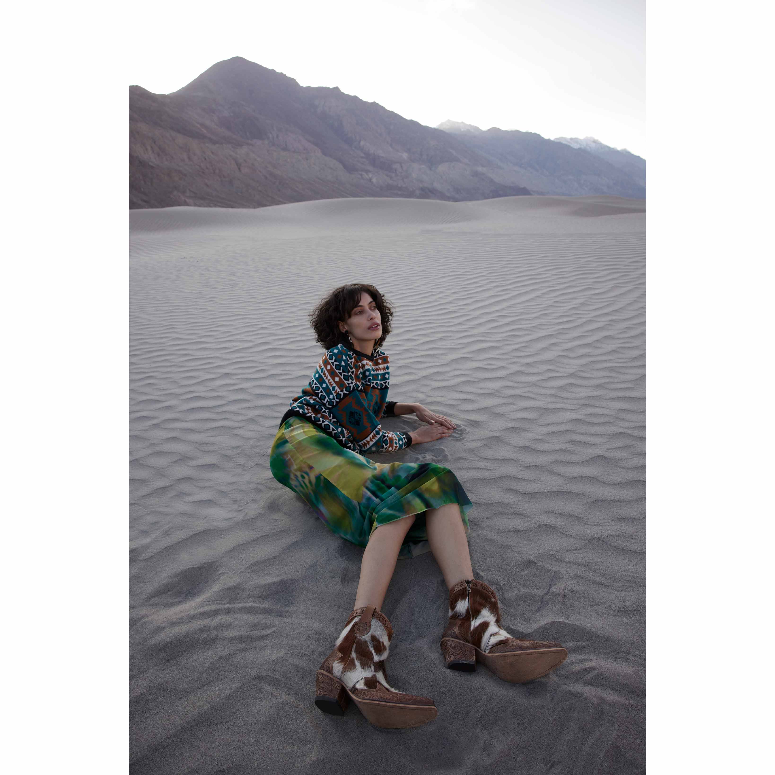 White and brown cowgirl boots with embossed floral patterns on the toe and heel areas