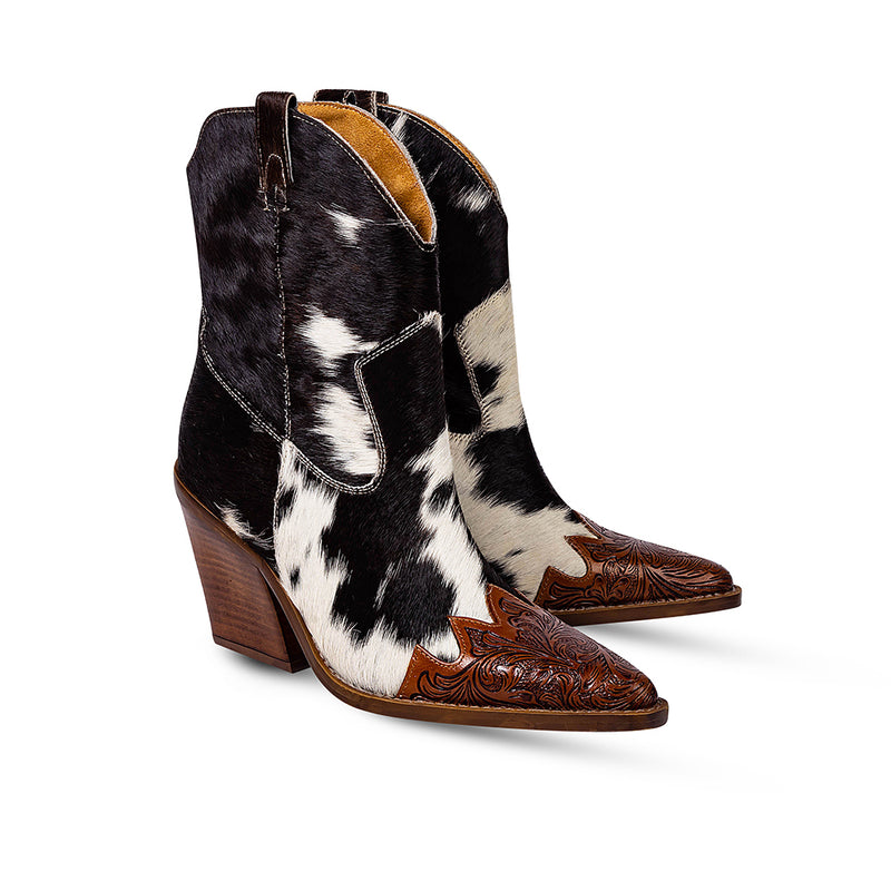 Cowgirl boots with a pointed toe and a mid-height heel featuring black and white cowhide leather