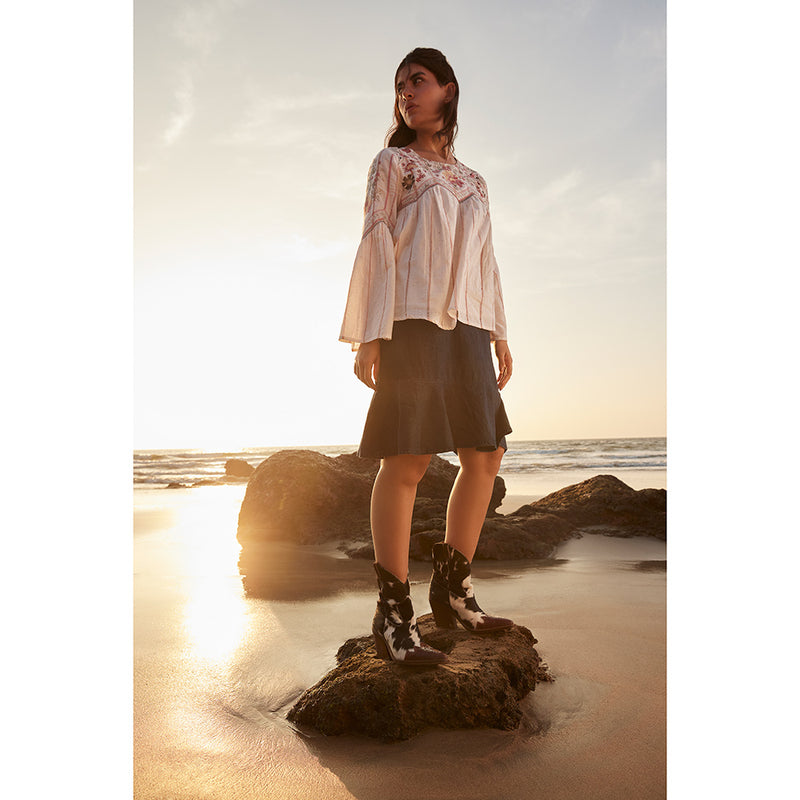 Cowgirl boots with a pointed toe and a mid-height heel featuring black and white cowhide leather