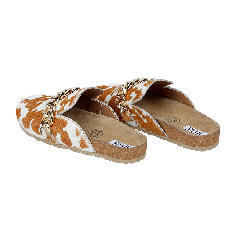 Brown and white cowhide slip-on slippers with golden chain detailing on the upper