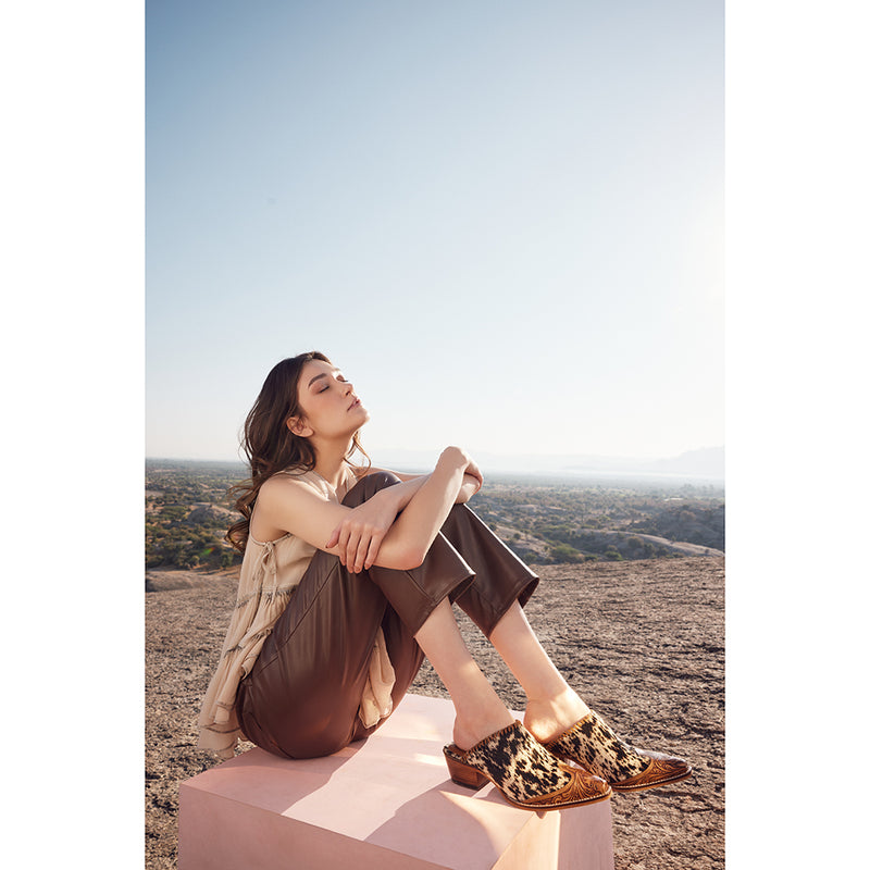 Handtooled western mules with pointed toe and black and white cowhide